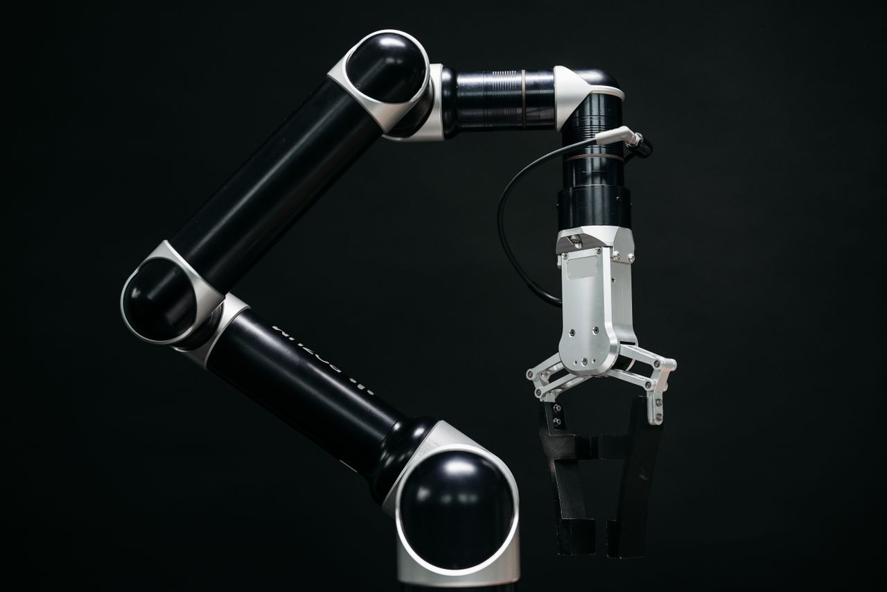 services-01 Close-up of a mechanical robotic arm with a dark background, showcasing advanced technology.